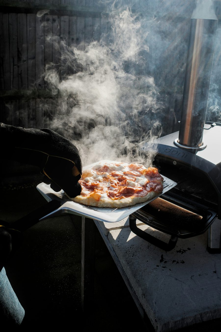 Steaming pizza fresh out of the oven on a pizza peel — Toscanacci Italian catering at home
